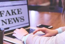 Benutzerin vor Laptop mit Text "Fake News" auf dem Monitor